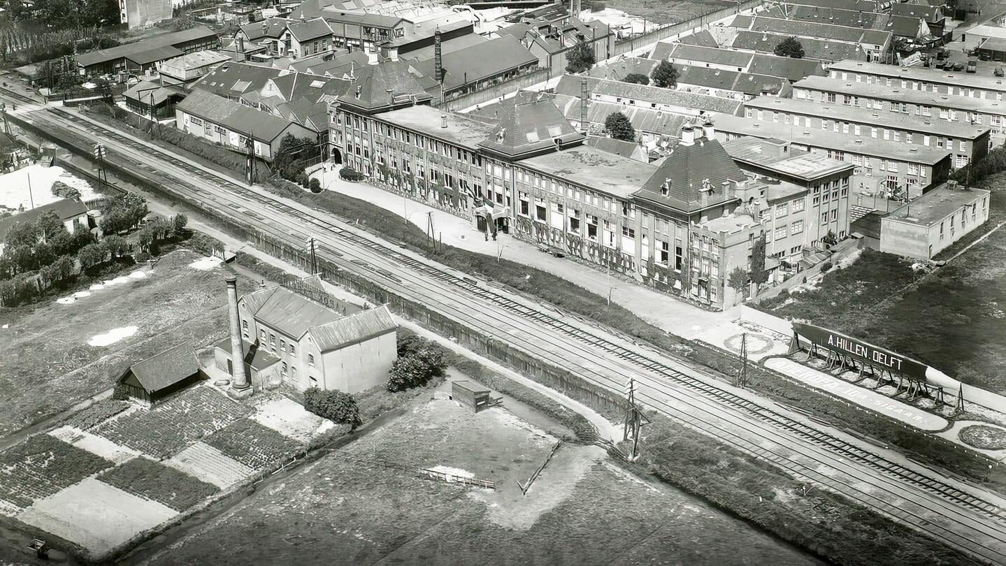 Luchtfoto van de sigarenfabriek A. Hillen langs de spoorlijn in Delft.