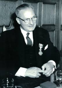 Zwart-witfoto van dr. Felix Hillen met bril en een onderscheiding op zijn jas.