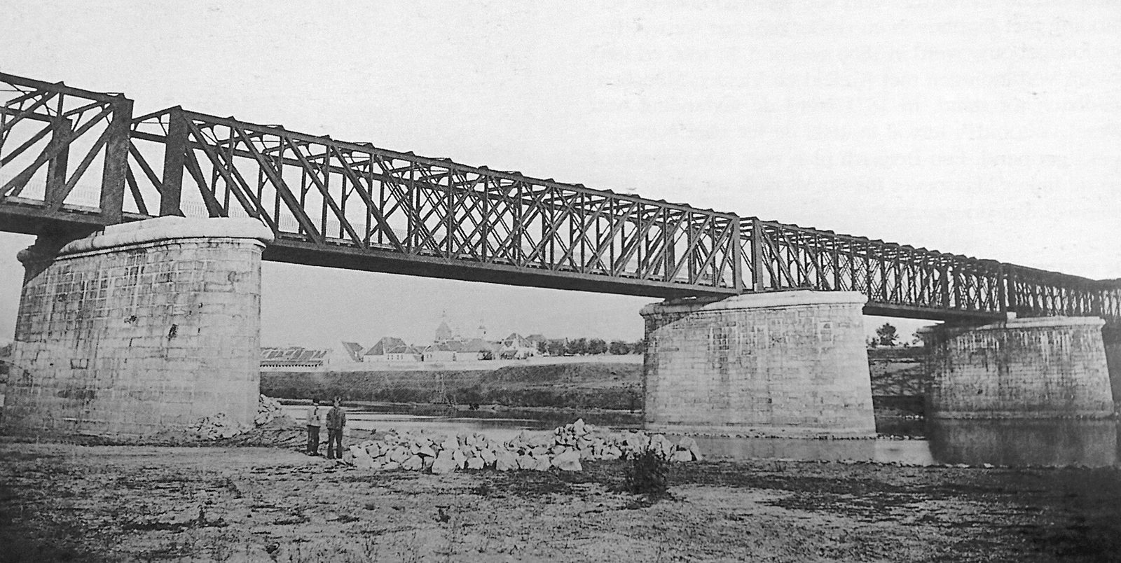 De nieuwe spoorbrug over de Maas in 1865, gezien vanaf de Blerickse oever: één ijzeren vakwerkbrug op stenen pijlers, met Venlo op de achtergrond.